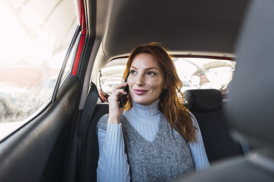 Smiling woman talking on smart phone in car
