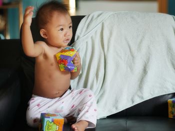 Cute baby girl sitting on bed at home