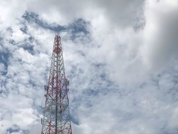 Low angle view of communications tower against cloudy sky