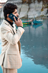 Full length of young man photographing while standing on water