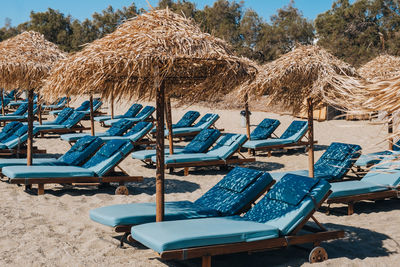 Empty blue sun beds and loungers under the umbrellas on a beach in mykonos, greece.