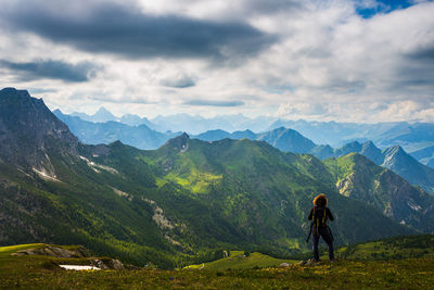 Rear view of man standing on mountain against sky