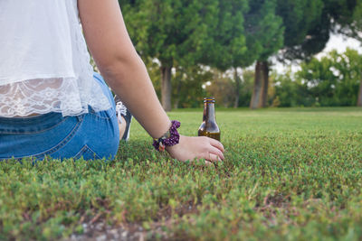 Low section of woman sitting on grassy field