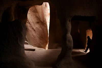 Rear view of silhouette person walking in cave