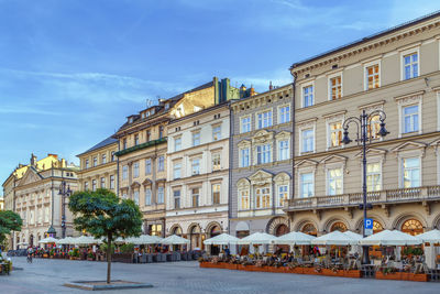 People on street by buildings against sky in city