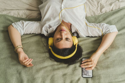 Midsection of woman sitting on bed at home