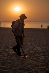 Silhouette man walking at beach during sunset