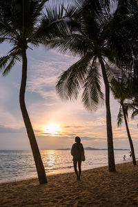 Silhouette woman standing at beach against sky during sunset