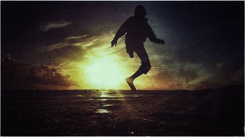 Silhouette woman jumping at sunset