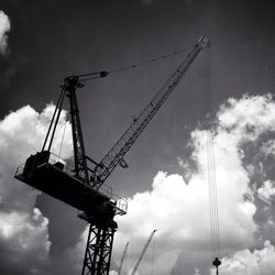 Low angle view of crane against cloudy sky