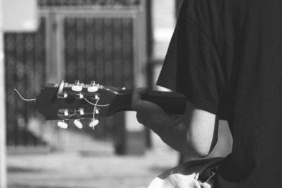 Midsection of man playing guitar sitting outdoors