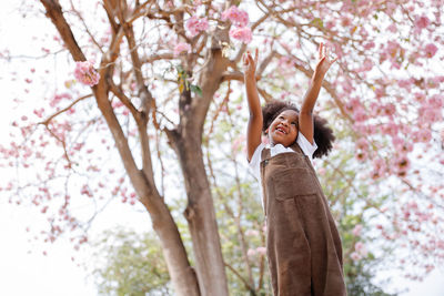 Woman standing by cherry blossom tree