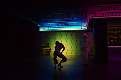 Full length of man and woman walking in illuminated building