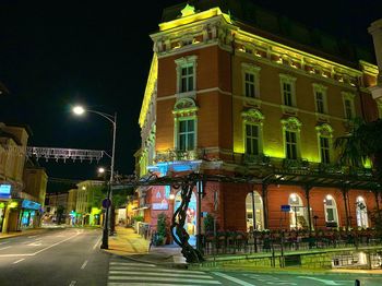 Illuminated street amidst buildings at night