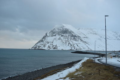 Scenic view of sea by snowcapped mountain against sky