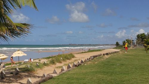 View of calm beach against blue sky and clouds