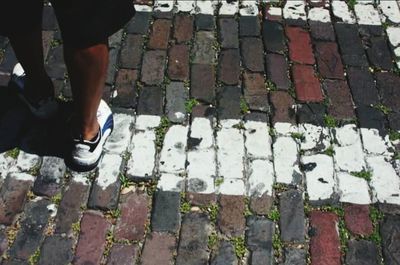 Low section of man standing on cobblestone