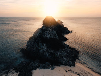 Rock formation on beach against sky during sunset