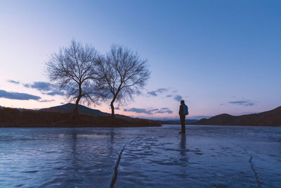 Man standing on frozen lake against sky