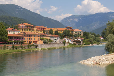 Houses by buildings and mountains against sky