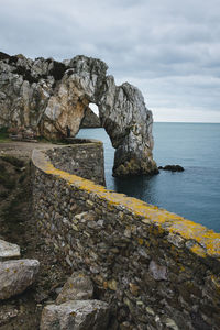 Rock formation by sea against sky