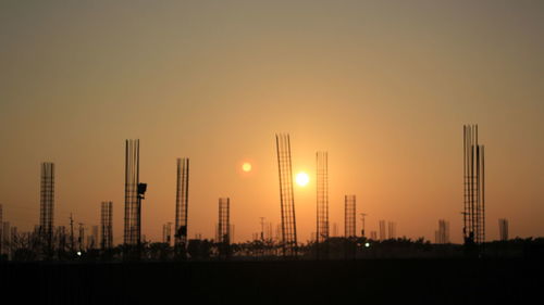 Silhouette factory against sky during sunset