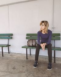 Portrait of young woman sitting on chair against wall