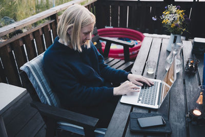 Woman using laptop on wooden table at holiday villa