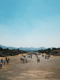 Group of people on landscape against clear sky