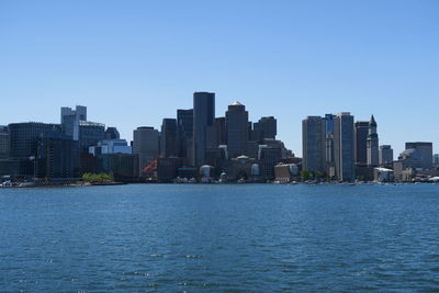 Sea by city skyline against clear sky