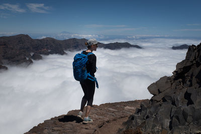 Full length of woman walking on rock by cloudscape against sky