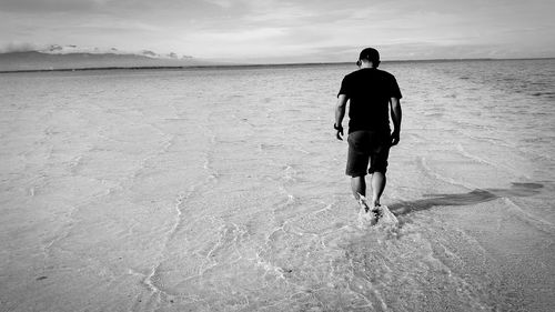 Full length rear view of man walking on beach