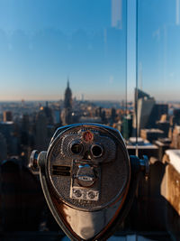 Close-up of coin-operated binoculars against cityscape