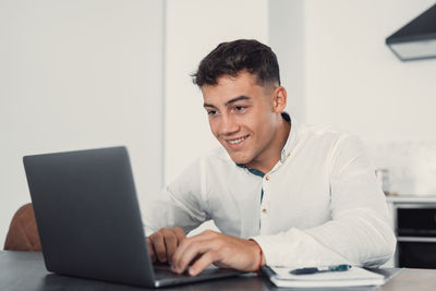 Young man using laptop at desk in office