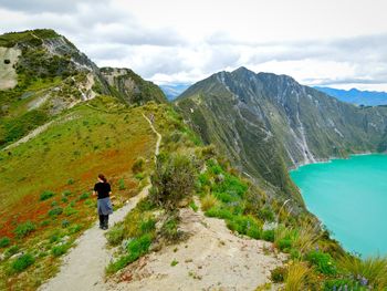 Rear view of man standing on mountain against sky