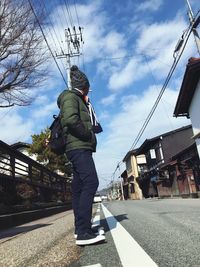 Low angle view of man using mobile phone against sky