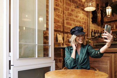 Portrait of a smiling young woman using phone in restaurant