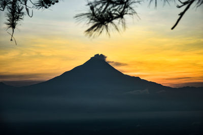 Silhouette of mountain against cloudy sky during sunset