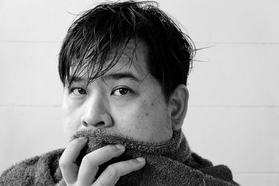 Close-up portrait of man standing against wall in bathroom at home