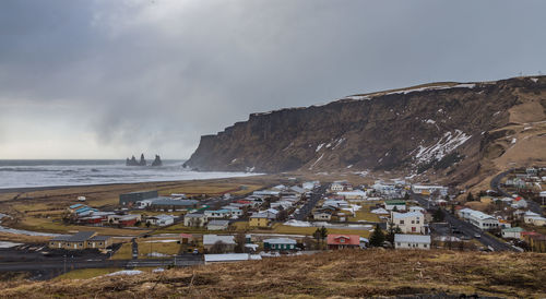 Scenic view of beach by buildings against sky