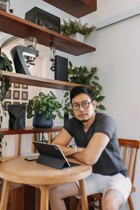 Portrait of woman using mobile phone while sitting on table