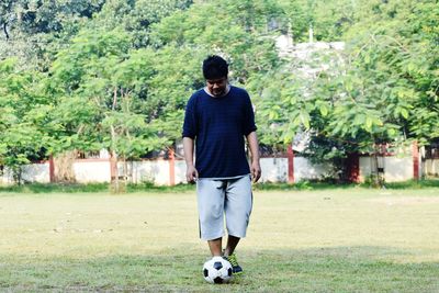 Rear view of man playing soccer at park