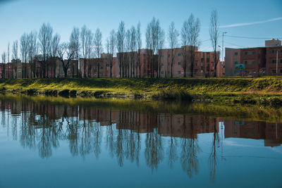 Scenic view of lake by trees and houses against sky