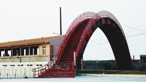 Red arch staircase in city against sky