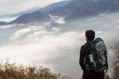 Rear view of man looking at mountains against sky