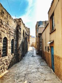 Narrow alley amidst residential buildings against sky