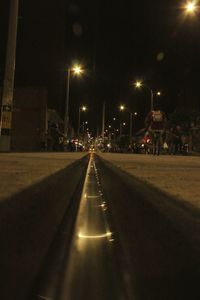 Surface level of road along illuminated street lights in city at night