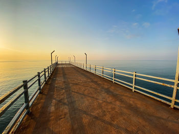 Pier over sea against sky during sunset