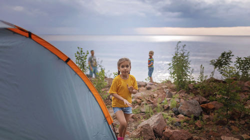 Family local getaway. kids with father having rest near camping tent at campsite, cloudy weather 