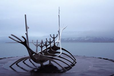 Metallic structure by sea against sky